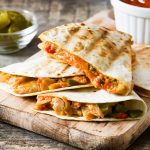 Mexican quesadilla with chicken, cheese and peppers on wooden ta